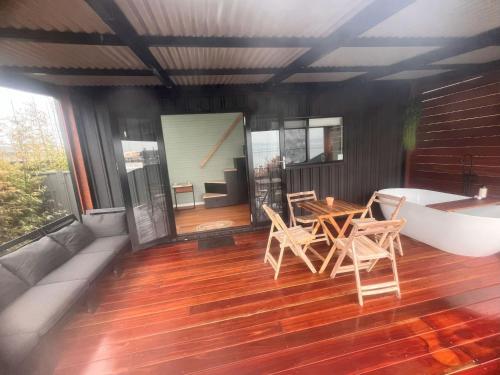 a room with a tub and a table and chairs on a deck at Cudgeree Tiny for Two in Windang