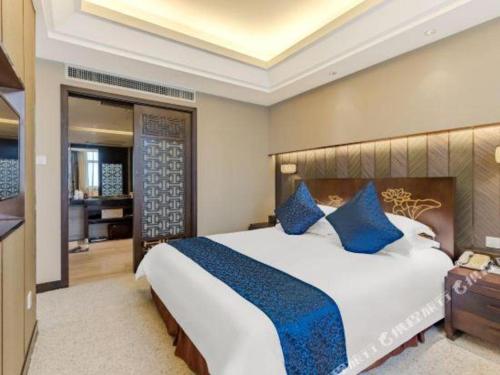 a large bedroom with a large bed with blue pillows at Dajiuhua Hotel in Chizhou