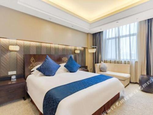 a hotel room with a large bed with blue pillows at Dajiuhua Hotel in Chizhou