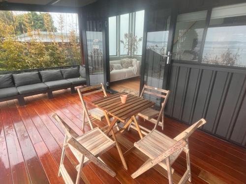 a patio with a table and chairs on a deck at Cudgeree Tiny for Two in Windang