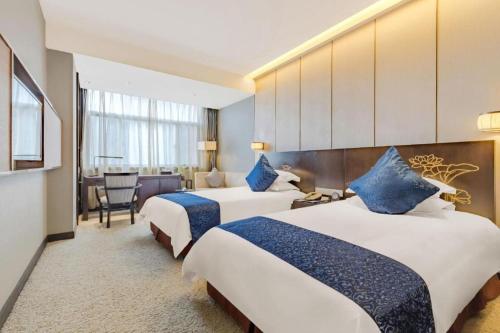 a hotel room with two beds with blue pillows at Dajiuhua Hotel in Chizhou