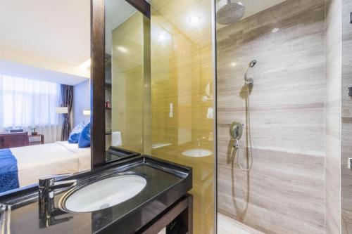 a bathroom with a sink and a shower and a bed at Dajiuhua Hotel in Chizhou