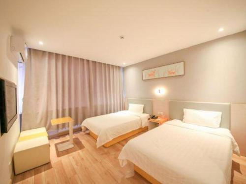 a hotel room with two beds and a television at 7 Days Inn·Ulanqab Tsining railway station in Ulanqab