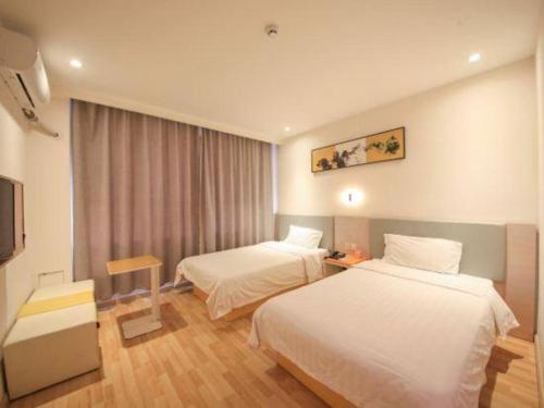 a hotel room with two beds and a television at 7 Days Inn·Ulanqab Tsining railway station in Ulanqab