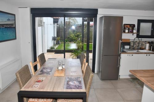 une table de salle à manger avec des chaises et une cuisine dans l'établissement Maison 7 pers 3ch 2 Sdb proche plages et golf, à Anglet