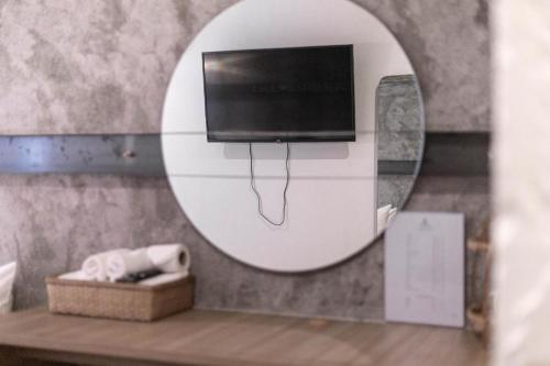 a mirror in a bathroom with a tv on a wall at The Singha Hotel - Korat in Nakhon Ratchasima