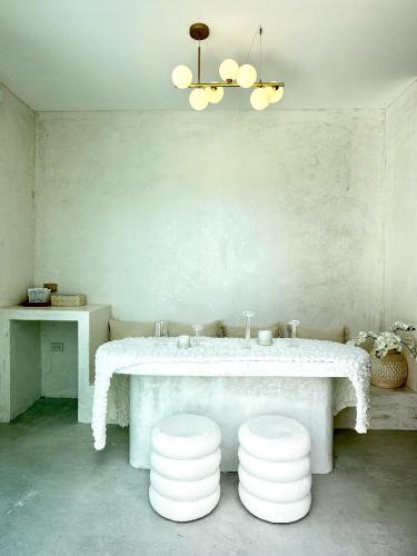 a dining room with a white table and stools at Evelia Kohsamed in Ao Phutsa