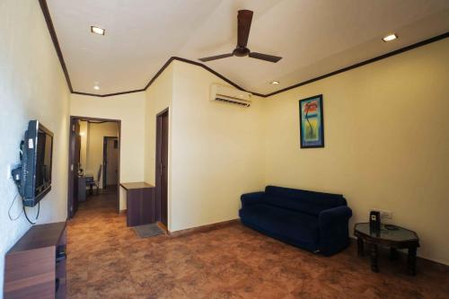 a living room with a blue couch and a ceiling fan at Adamo The Village in Matheran