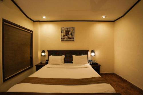 a bedroom with a bed and a large window at Adamo The Village in Matheran