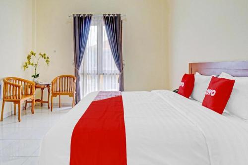 a bedroom with a large bed and a table with chairs at Collection O 90693 ORCHID EDOTEL Boyolangu in Tulungagung