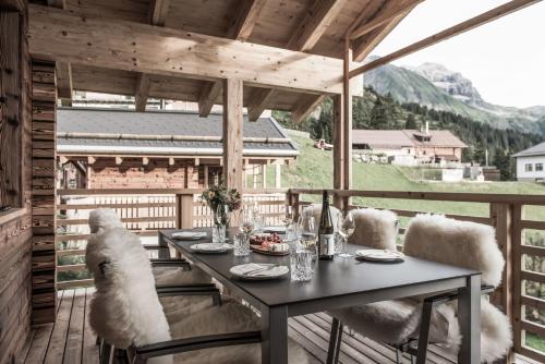 a dining table on a deck with a view of a mountain at Aadla Walser-Chalets mit privater Sauna, Hotpot und Hotelservice in Schröcken