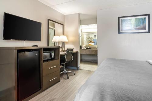 a hotel room with a bed and a desk with a television at Quality Inn Simpsonville-Greenville in Simpsonville