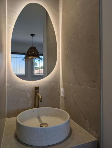 La salle de bains est pourvue d'un lavabo rond et d'un miroir. dans l'établissement T2 Cocon à 5 min de la plage Calme & Confort, à Saint-Raphaël
