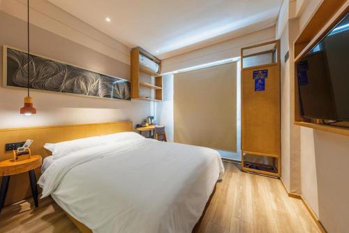 a bedroom with a white bed and a television at V8 Ziyuangang Hotel in Guangzhou