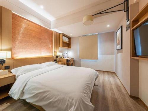 a bedroom with a large white bed and a television at V8 Ziyuangang Hotel in Guangzhou