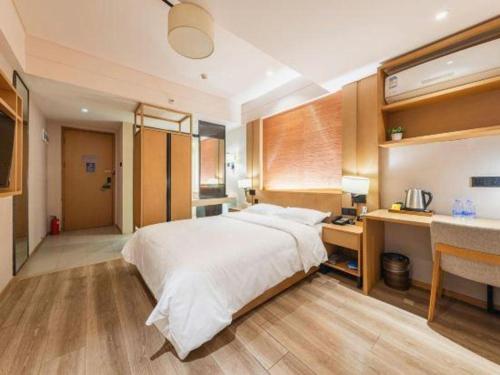a bedroom with a large bed and a desk at V8 Ziyuangang Hotel in Guangzhou