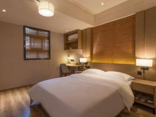 a bedroom with a large white bed and a desk at V8 Ziyuangang Hotel in Guangzhou