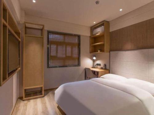 a bedroom with a large white bed and a television at V8 Ziyuangang Hotel in Guangzhou