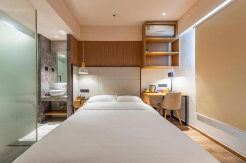 a bedroom with a large white bed and a desk at V8 Ziyuangang Hotel in Guangzhou