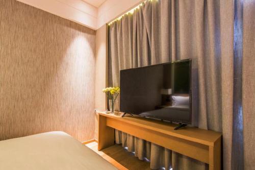a hotel room with a flat screen tv and a bed at V8 Ziyuangang Hotel in Guangzhou