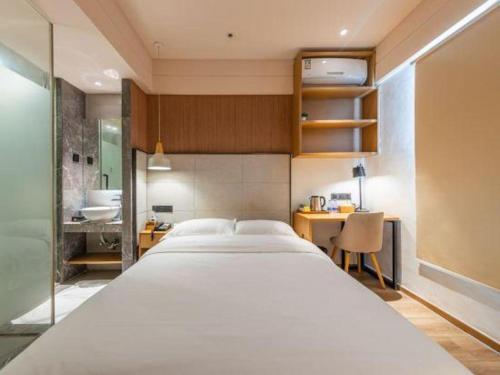 a bedroom with a large white bed and a bathroom at V8 Ziyuangang Hotel in Guangzhou