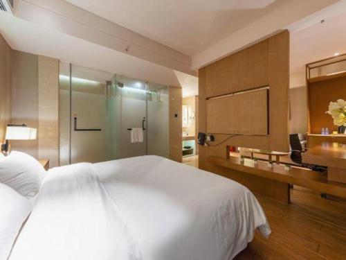 a bedroom with a large white bed and a bathroom at V8 Ziyuangang Hotel in Guangzhou