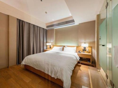 a bedroom with a large white bed and a desk at V8 Ziyuangang Hotel in Guangzhou