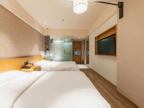 a bedroom with two beds and a flat screen tv at V8 Ziyuangang Hotel in Guangzhou