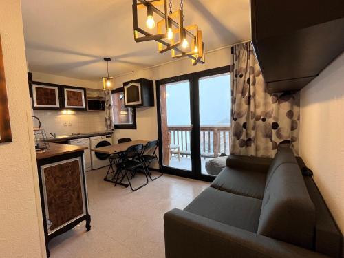 Il comprend un salon avec un canapé et une cuisine avec un balcon. dans l'établissement Le 72ème flocon, T2, vue imprenable, résidence calme, 100 m des pistes, à Saint-Étienne-en-Dévoluy