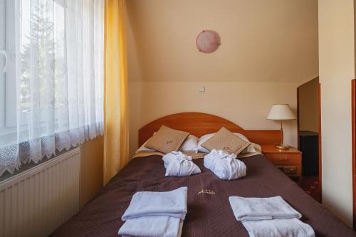a bedroom with a bed with towels on it at Kompleks Antałówka Termy & Med in Zakopane