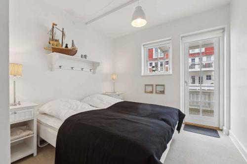 a bedroom with a bed and a desk and two windows at Lovely Holiday Home With Harbor View in Bagenkop