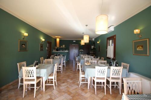 a dining room with tables and chairs and green walls at Oasi di Arcadia in Santa Giulia