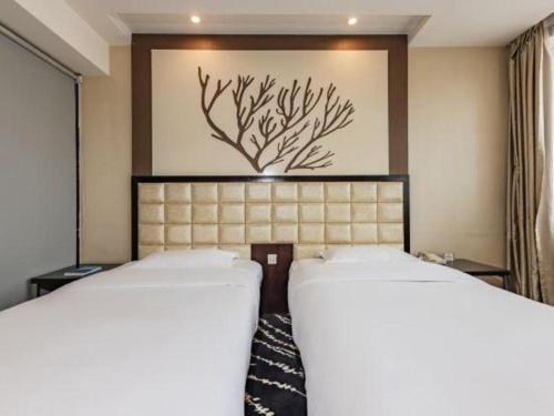 a bedroom with two beds and a painting on the wall at Kunming Long Way Hotel in Kunming