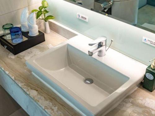 a white sink in a bathroom with a mirror at Kunming Long Way Hotel in Kunming