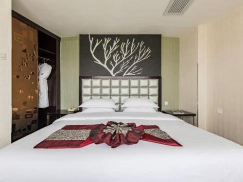 a bedroom with a white bed with a bow on it at Kunming Long Way Hotel in Kunming