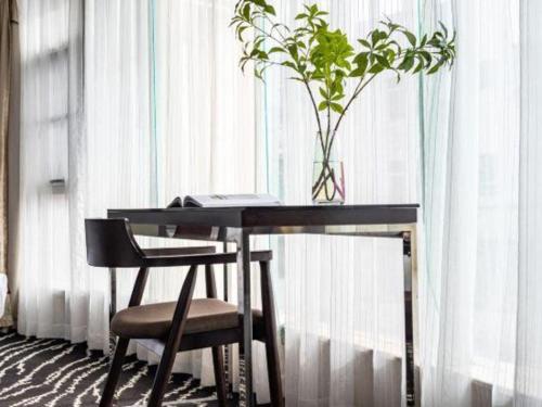 a desk with a chair and a plant in a window at Kunming Long Way Hotel in Kunming