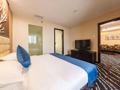 a bedroom with a large bed and a flat screen tv at Kunming Long Way Hotel in Kunming