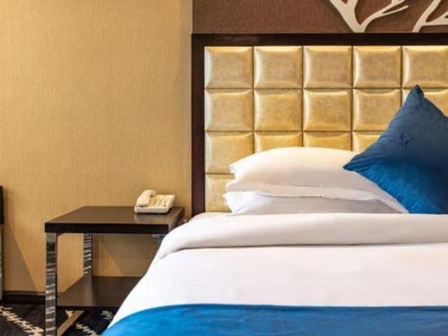 a bedroom with a bed and a phone on a table at Kunming Long Way Hotel in Kunming