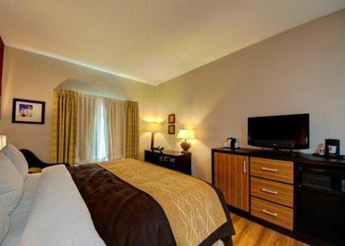 a bedroom with a bed and a flat screen tv at Comfort Inn & Suites Tulsa I-44 West - Rt 66 in Tulsa
