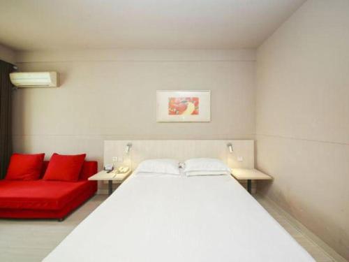a bedroom with a bed and a red couch at Jinjiang Inn Liaocheng Wanda Plaza Jianshe West Road in Liaocheng