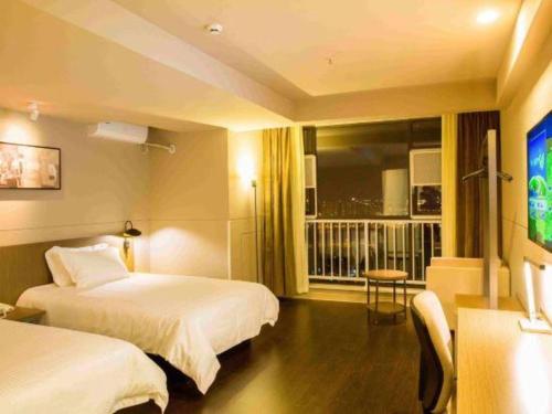 a hotel room with two beds and a flat screen tv at Jinjiang Inn Select Kunming High-speed South Railway University Town in Kunming