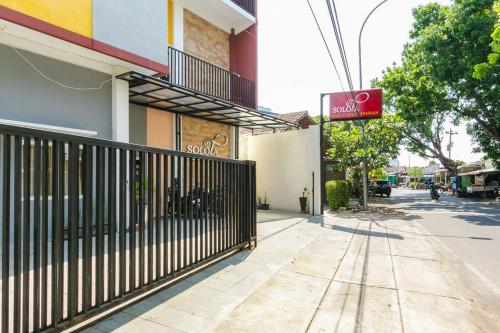 a building with a gate in front of a street at RedDoorz Syariah near Purwosari Train Station in Solo