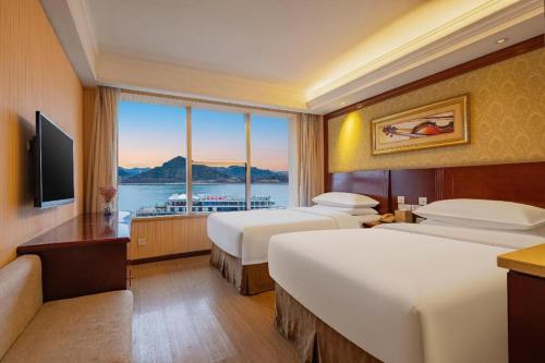 a hotel room with two beds and a large window at Yichang Vienna Hotel Wanda Branch in Yichang