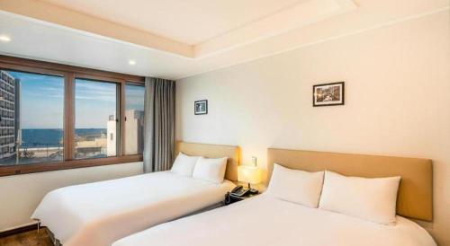 a hotel room with two beds and a window at Check Inn Hotel in Jeju