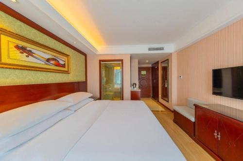 a bedroom with a large white bed and a flat screen tv at Yichang Vienna Hotel Wanda Branch in Yichang