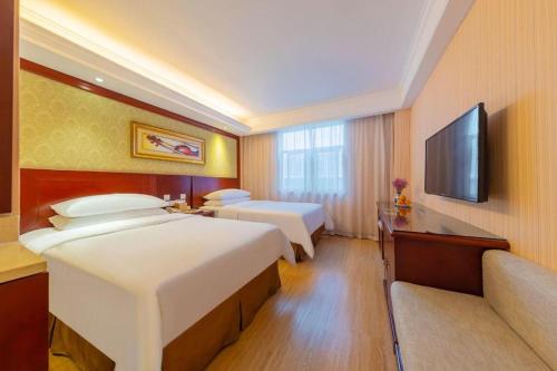 a hotel room with two beds and a flat screen tv at Yichang Vienna Hotel Wanda Branch in Yichang