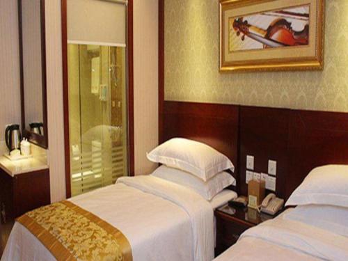 a hotel room with two beds and a mirror at Yichang Vienna Hotel Wanda Branch in Yichang
