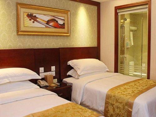 a hotel room with two beds and a mirror at Yichang Vienna Hotel Wanda Branch in Yichang