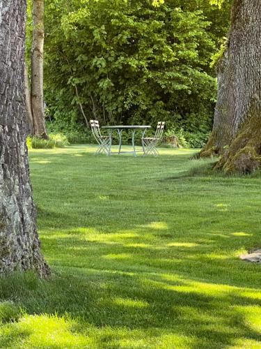 a table and chairs in a field with trees at Herrenhaus - Starnberger See - Ammerland in Münsing am Starnberger See