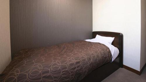 a bedroom with a bed with a brown bedspread at Business Hotel Wako in Ichinomiya